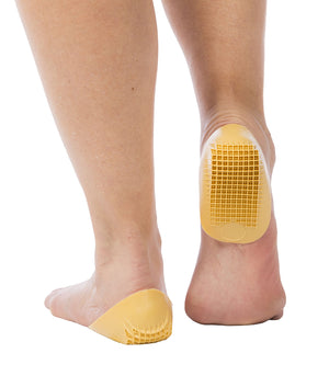 Yellow gel heel cups on bare feet with textured grip pattern on the bottom.