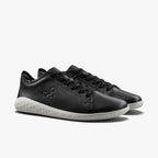 Black leather low-top sneakers with white textured soles and subtle logo on the side.