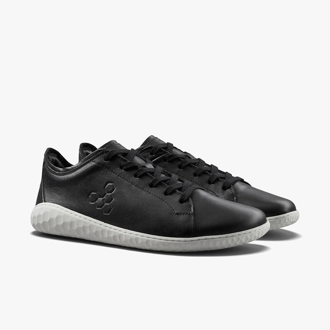 Black leather low-top sneakers with white textured soles and subtle logo on the side.