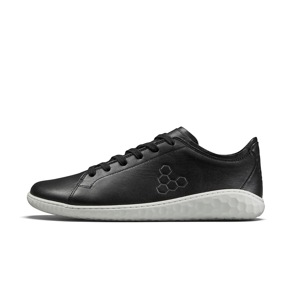 Black leather low-top sneaker with honeycomb logo and textured white sole.
