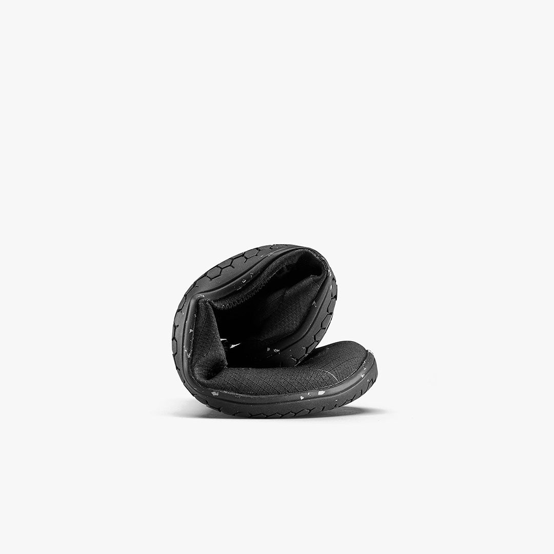 Black flexible athletic shoe bent in half showing sole and upper details.