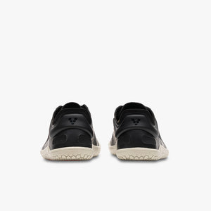 Black Vivobarefoot Primus Lite IV All Weather shoes with beige textured soles, rear view.