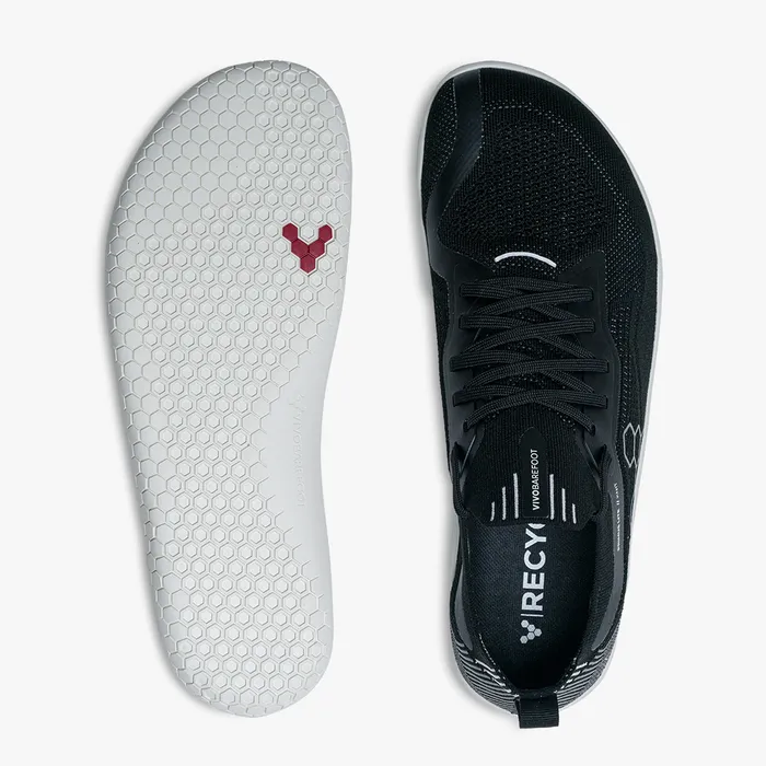 Black knitted athletic shoe with laces and white honeycomb-patterned sole with red logo.