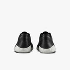 Pair of black leather low-top sneakers with white soles, viewed from the back with embossed logo on heels.