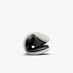 Flexible black leather athletic shoe folded to show soft sole and flexibility with white textured outsole.