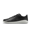 Black leather low-top sneaker with white textured sole and hexagon logo on side.