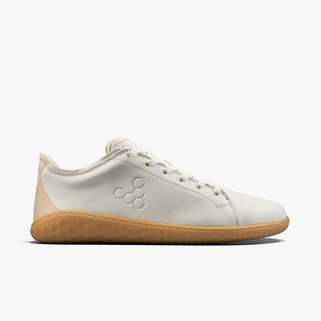 Low-profile white leather sneaker with gum rubber sole and subtle honeycomb logo on side.