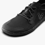Close-up of black breathable mesh Vivobarefoot athletic shoe with minimalist sole and hexagonal logo on side.