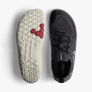 Black knit low-profile athletic shoe with white textured sole and red hexagonal tread accents.