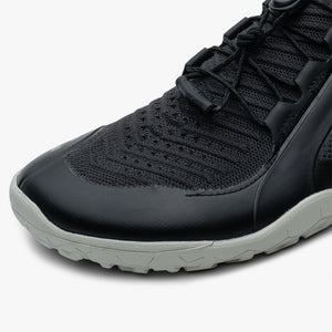 Black knit athletic shoe with synthetic overlays and textured gray sole, lace-up design.