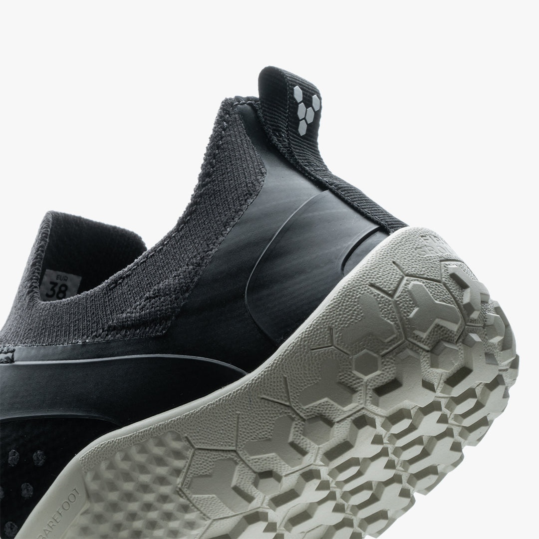Black and gray knit trail shoe with hexagonal-patterned white sole and pull tab at heel.
