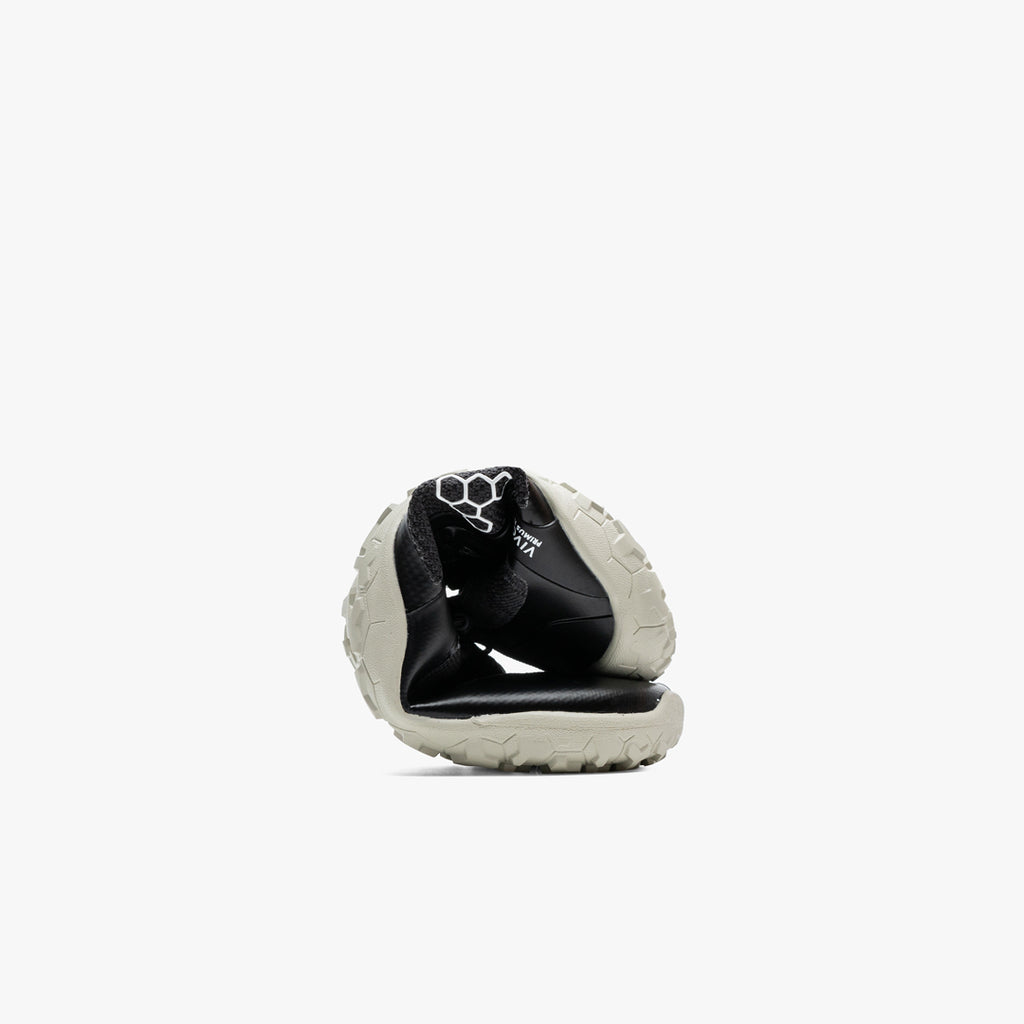 Folded black and off-white Vivobarefoot athletic shoe with flexible sole and knit upper.