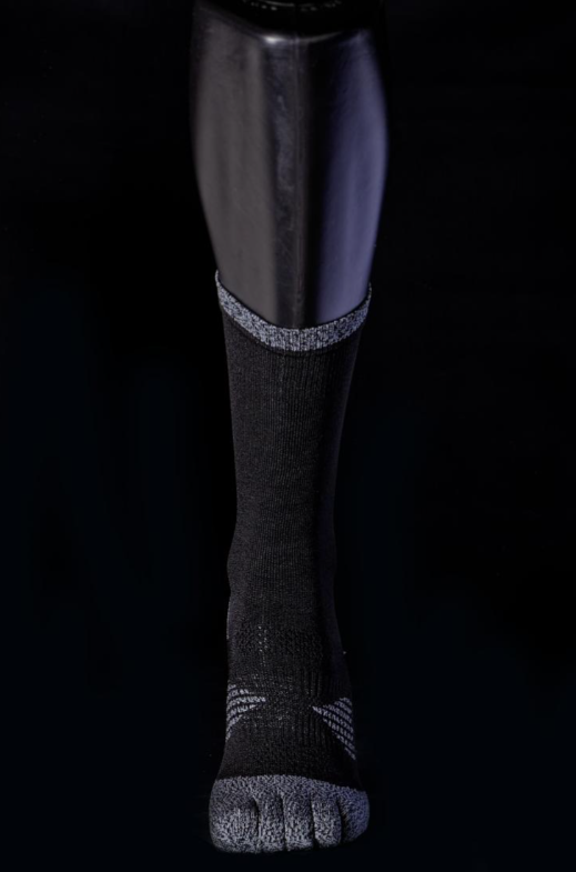 Black and grey crew sock with reinforced toe and heel details shown on a mannequin leg against a black background.