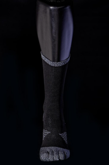 Black and grey crew sock with reinforced toe and heel details shown on a mannequin leg against a black background.
