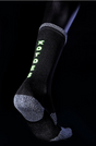 Black and grey crew sock with neon green vertical "XOTOES" logo on the side, textured heel and toe areas.