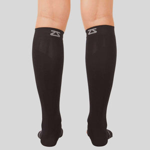 Black compression ankle and calf sleeves with gray Zensah logo on back upper cuff worn on legs.