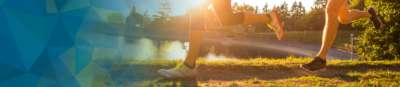 Sunset in background with two runners by a lake